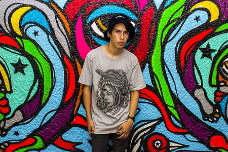 man standing beside graffiti wall thumbnail