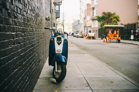 blue and white motor scooter beside wall thumbnail