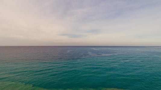 body of water with calm waves under cumulus clouds thumbnail