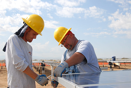 two men in yellow hard hat helmets installing solar panels during daytime thumbnail