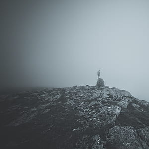 greyscale photography of person standing on stone formation thumbnail