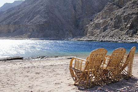 three brown rattan armchairs near body of water at daytime thumbnail