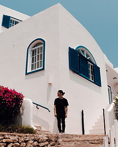 man standing beside white concrete house thumbnail