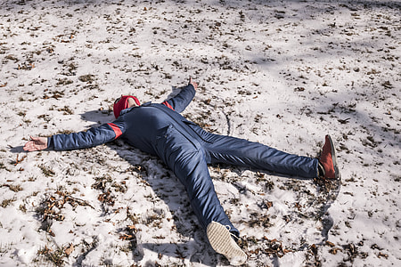 person in blue overalls lying on snow during daytime thumbnail