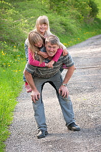 man carrying two girls beside road thumbnail
