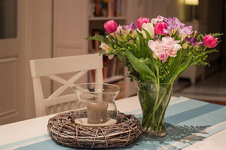bunch of flowers in vase beside clear glass candle holder thumbnail