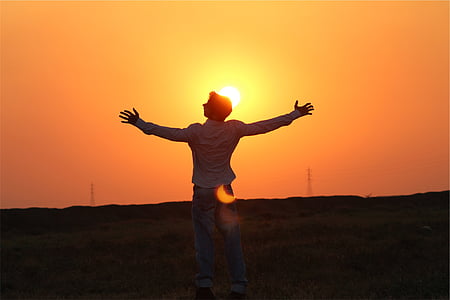 man in white dress shirt standing on green grass field during sunset thumbnail