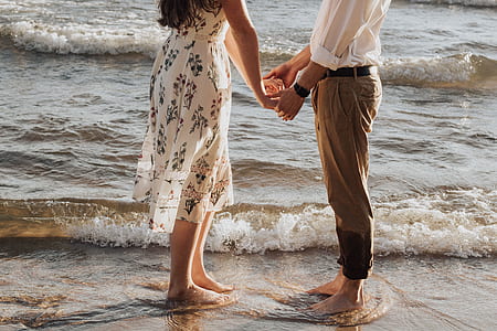 couple holding hands while standing on seashore thumbnail