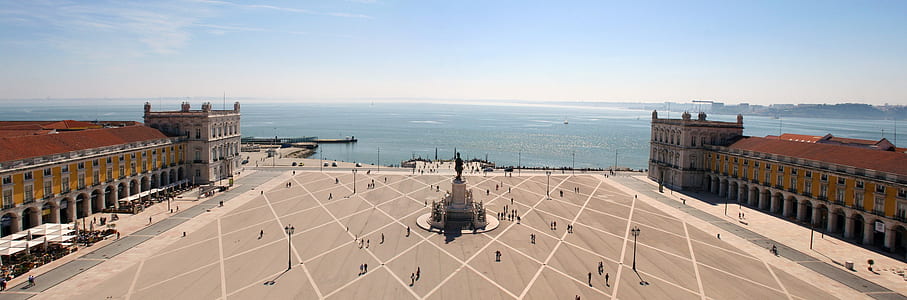 brown statue between brown concrete buildings near sea during daytime thumbnail