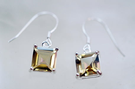 closeup photography of silver-colored hook earrings with yellow gemstone thumbnail