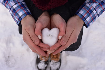 two person holding silver-colored ring on block of snow thumbnail