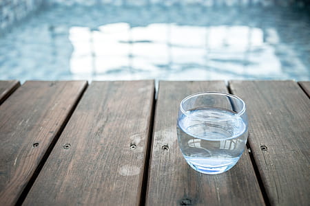 selective focus photography of rock glass filled with water near pool thumbnail
