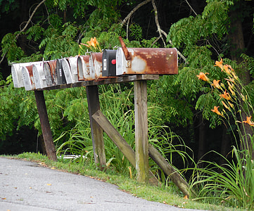 assorted-color mail post beside road at daytime thumbnail