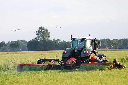 black and orange harvester on green grass field thumbnail