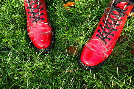 pair of cherry red Dr. Martens 1460 boots on green grass thumbnail