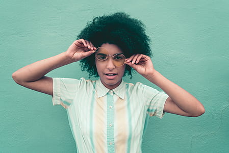 woman wearing green and brown button-up collared t-shirt holding hippie eyeglasses thumbnail