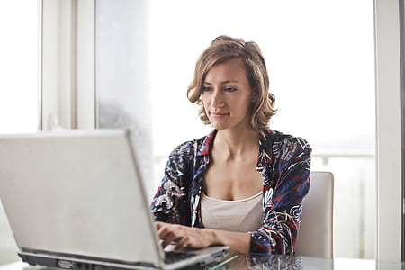 A young blonde woman working on her laptop in the office during the day time thumbnail