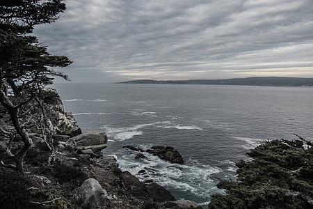 sea near mountain under white clouds thumbnail