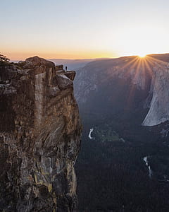 person on mountain near cliff during sunrise thumbnail