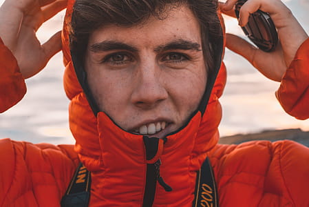 closeup photography of man wearing orange jacket thumbnail