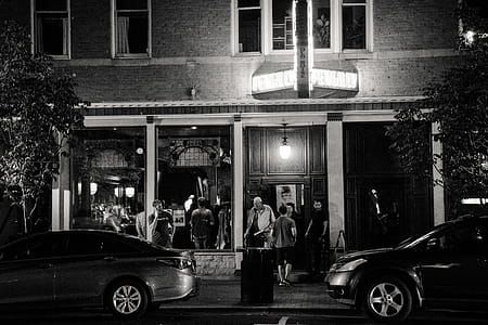 Grayscale Photography Of Two Vehicles Parked Near Building thumbnail