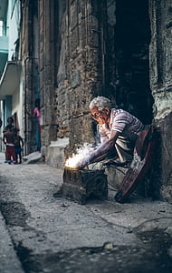 man sitting on concrete working on vehicle engine during daytime thumbnail