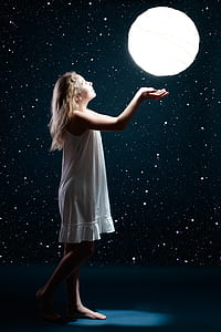 girl wearing whit sleeveless dress looking to round white hanging paper lamp thumbnail