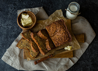 loaf breads on brown chopping board with knife and bowl of butter thumbnail