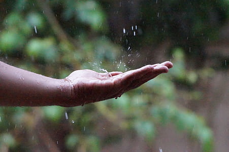 persons left hand catching the raindrops during daytime thumbnail