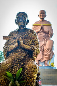 Thai monk in Ayudhaya, Thailand - contrasting statues. thumbnail