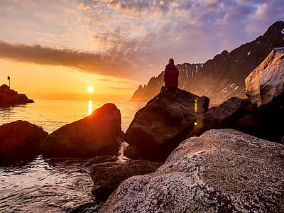 Person Sitting on Rock Formation Beside Body of Water thumbnail