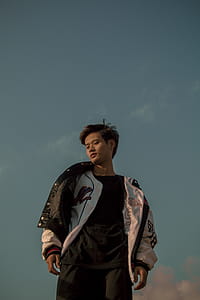 Man in White Jacket Standing Under Blue Skies thumbnail