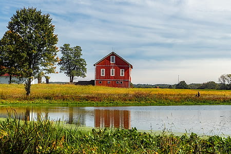 red 3-storey house on grass field near lake thumbnail