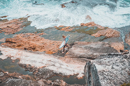 person holding surfboard walking on shore at daytime thumbnail
