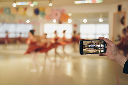 person holding smartphone taking video of dancing women thumbnail