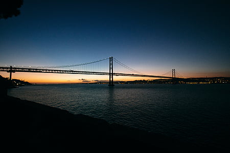 black suspension bridge on sea taken during night time thumbnail
