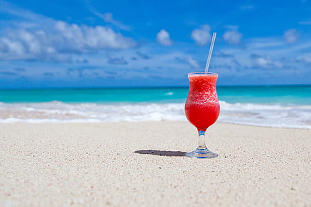 clear footed glass cup filled with smoothie on seashore thumbnail