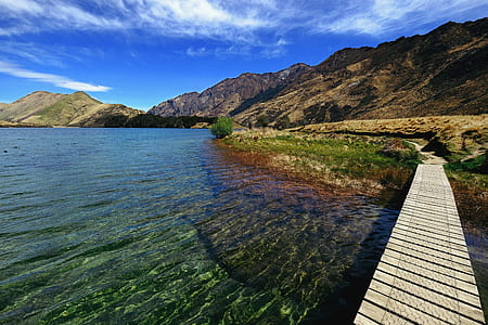 mountains near body of water under blue sky thumbnail