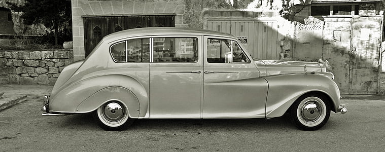 grayscale photo of classic vehicle parked near gate and store thumbnail
