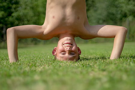 boy playing on grass field during daytime thumbnail