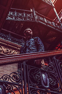 man looking sideways while standing beside stairs thumbnail