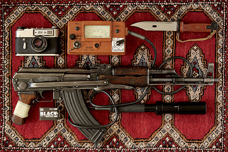 black and brown AK-47 near black and gray camera and tactical knife place on red and gray area rug thumbnail