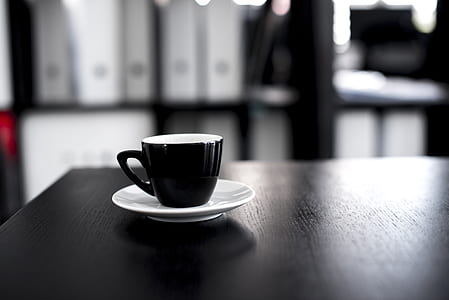 black teacup on white saucer over table thumbnail