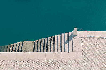 aerial photography of white concrete staircase beside body of water during day thumbnail