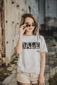 woman wearing gray and black Dale t-shirt and beige denim short shorts touching her sunglasses thumbnail