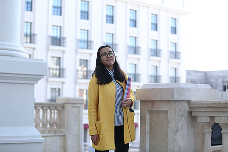 woman wearing yellow cardigan while holding pink book thumbnail