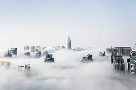 city buildings surrounded with clouds at daytime thumbnail