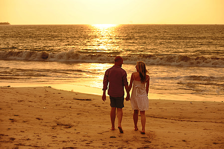 couple holding each other while walking beside beach thumbnail