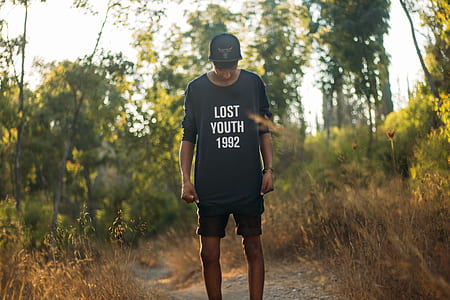 man in black lost youth 1992-printed crew-neck sweater standing between brown grass during daytim thumbnail