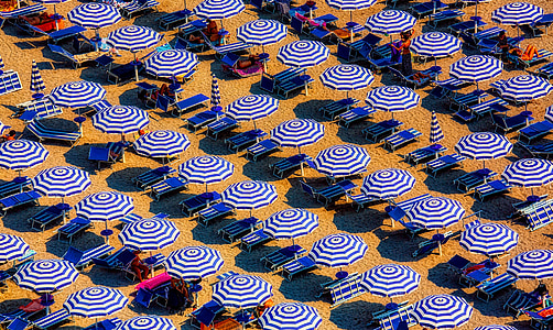 blue-and-white umbrella lot on white sand thumbnail